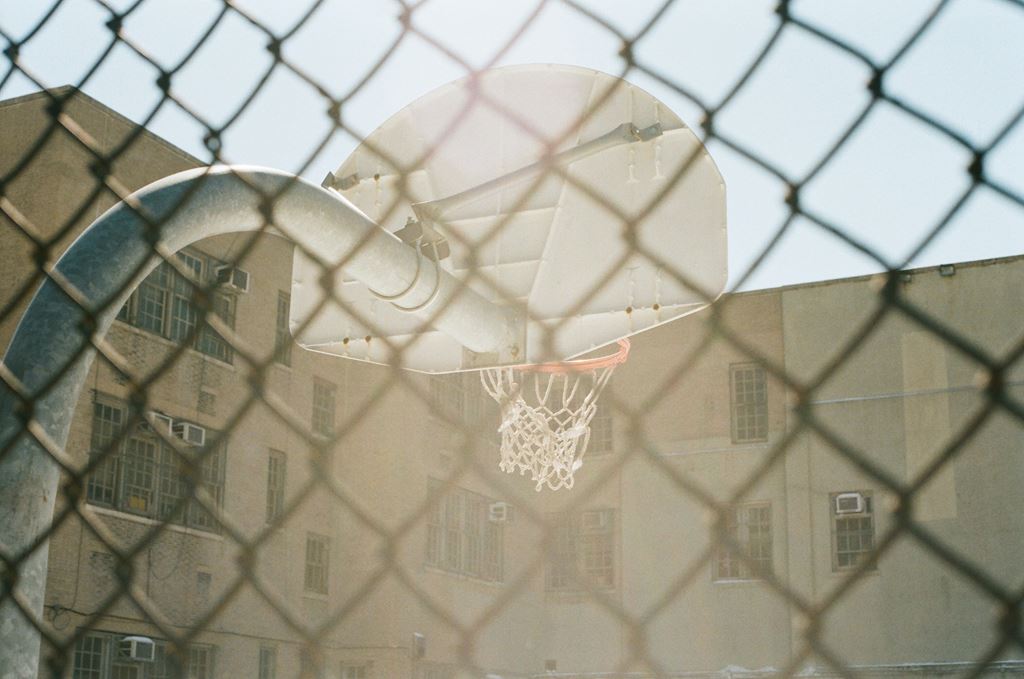 Basketball hoop backboard viewed through a fence 