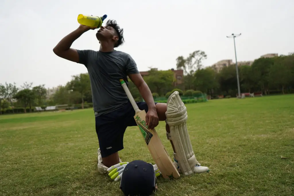 Hydration is important for sports nutrition. Here a man is playing cricket and stopping for a quick drink.