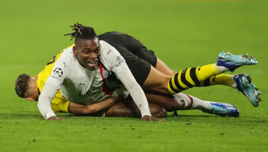 Two players tustling on the floor in the AC Milan vs Dortmund game
